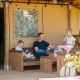 Familia relajándose en la terraza de la tienda Safari Meddo con muebles de madera y flores.