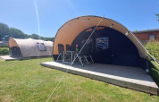 Tunnel telte ved Sevink Molen campingplads i Holland, med træterrasse og stole i sommervejr.