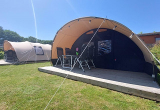 Tiendas tipo túnel en el camping Sevink Molen en Países Bajos, con terraza de madera y sillas afuera.