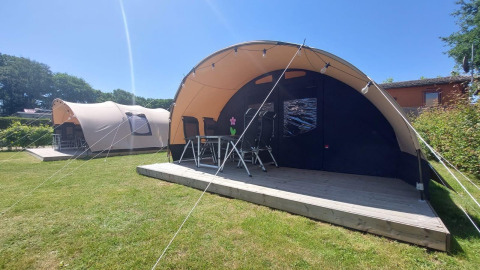 Tunnel tents at Sevink Molen campsite in the Netherlands, with wooden decks and camping chairs outside.
