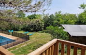 View from a wooden terrace over a fenced pool, blue loungers, and a safari tent at Domaine La Sauzette, France.