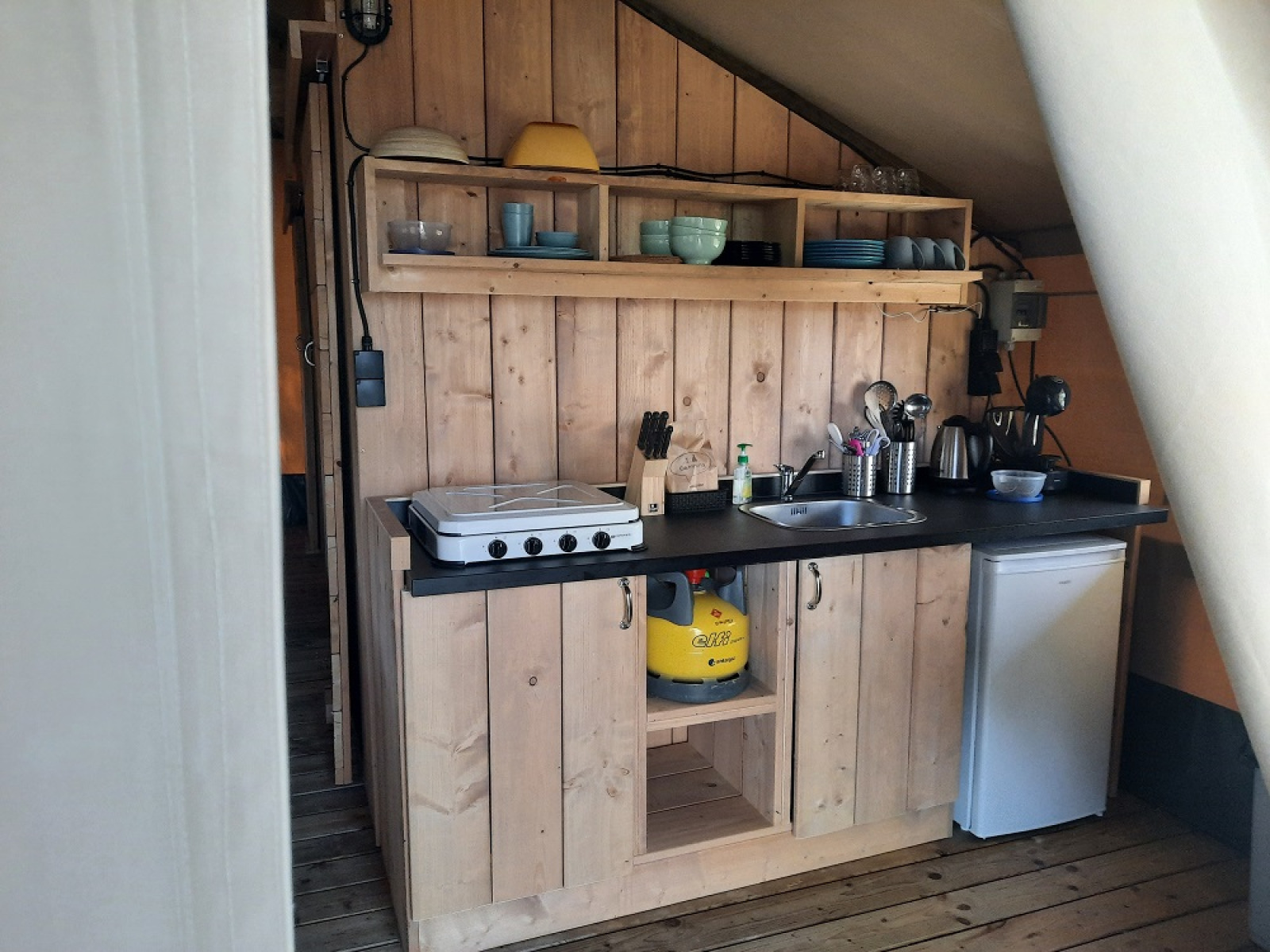 Keukentje in een safaritent bij Domaine La Sauzette in Frankrijk, met houten kastjes en gasfornuis.