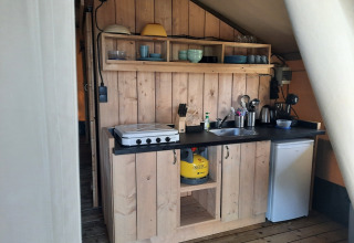 Keukenhoek in een safaritent bij Domaine La Sauzette in Frankrijk met houten kasten en gasvuur.