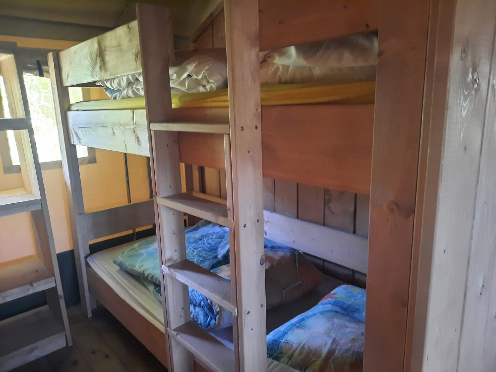 Houten stapelbedden in een gezellige safaritent met raam op Domaine La Sauzette, Frankrijk.