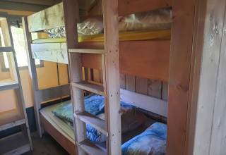 Houten stapelbedden in een sfeervolle safaritent met venster op Domaine La Sauzette, Frankrijk.