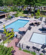 Zona de piscinas en Bospark Ede, parque vacacional en Gelderland, Países Bajos, rodeada de tumbonas y sombra.