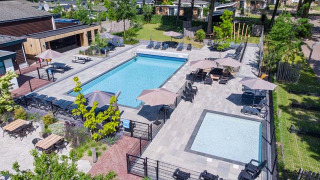 Zona de piscinas en Bospark Ede, parque vacacional en Gelderland, Países Bajos, rodeada de tumbonas y sombra.