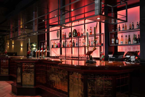 Elegante bar con estantes iluminados y botellas en Bospark Ede, parque vacacional en Gelderland, Países Bajos.