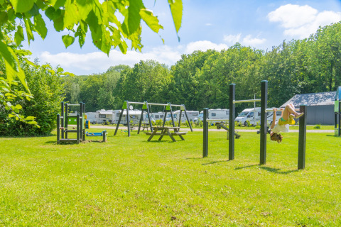 Parco giochi con altalene e caravan presso Camping de Boskant, parco vacanze a Limburg, Paesi Bassi.