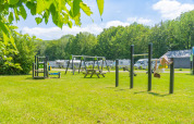 Smuk legeplads med gynger og klatrestativer ved Camping de Boskant i Limburg, Holland, omgivet af natur.