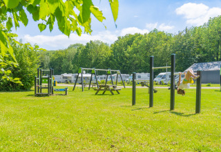 Parque infantil con columpios y caravanas en Camping de Boskant, un parque vacacional en Limburg, Países Bajos.