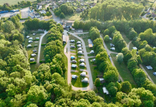Luftfoto af Camping de Boskant feriepark i Limburg, Holland, omgivet af træer og campingvogne.