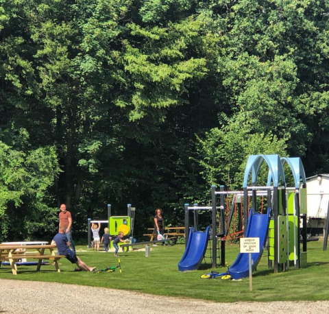 Niños juegan en toboganes azules y columpios en Camping de Boskant, parque vacacional en Limburg, Países Bajos.