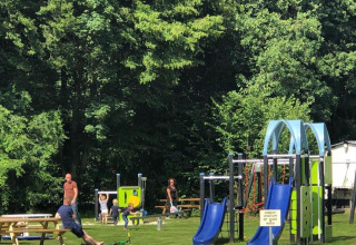 Children play on blue slides and playground equipment at Camping de Boskant holiday park in Limburg, Netherlands.
