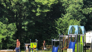 Kinder spielen auf einem Spielplatz mit Rutschen im Ferienpark Camping de Boskant, Limburg, Niederlande.