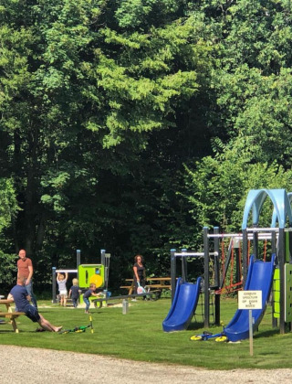 Niños juegan en toboganes azules y columpios en Camping de Boskant, parque vacacional en Limburg, Países Bajos.