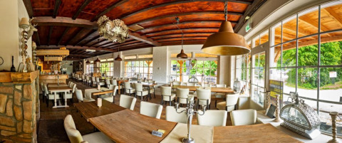 Panoramaaufnahme eines Restaurants mit Holzbalkendecke und großen Fenstern im Camping de Boskant in Limburg, Niederlande.