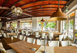 Panoramisch zicht van een gezellig restaurant met houten plafond en grote ramen op Camping de Boskant, Limburg.