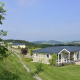 Calcelux-hytte ved Camping & Ferienpark Brilon i Tyskland, omgivet af grønne bakker og klar himmel.