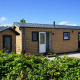 Moderne træhytte Chalet Alme på Camping & Ferienpark Brilon, omgivet af grønt og blå himmel.
