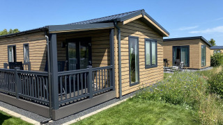 Cabaña Chalet Waldfee con terraza en Camping & Ferienpark Brilon, Alemania, rodeada de césped y flores silvestres.