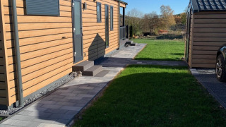 Vista soleada del Chalet Bergrose en Camping & Ferienpark Brilon, Alemania, con césped verde cuidado.