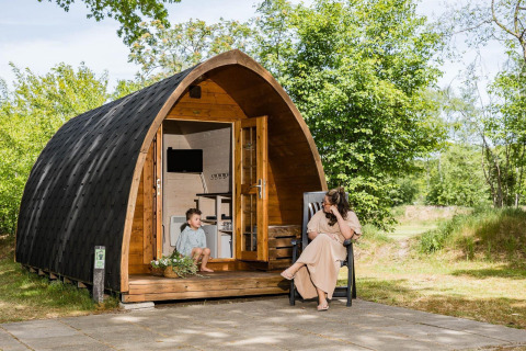 Moeder en kind genieten samen aan een knusse pod in Kampeerdorp de Zandstuve, omringd door natuur.