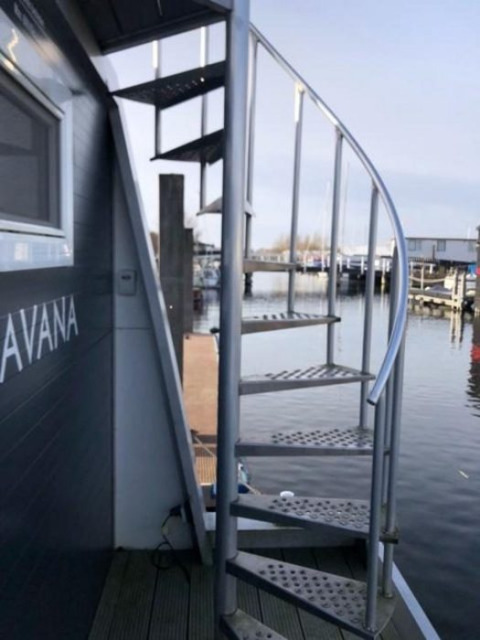 Spindeltreppe außen an einem Gebäude mit Blick auf Steg und Boote, Marina Parcs - Jachthaven De Hoop, Nordholland.