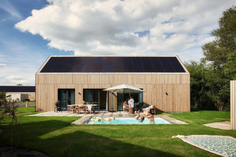 Unbrick One lodge con sauna, piscina y paneles solares, familia disfruta en cabaña moderna de madera.