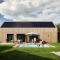 Unbrick One lodge met sauna, zwembad en zonnepanelen, gezin geniet buiten bij moderne houten woning.