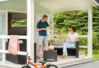 Coppia che si gode una bevanda sulla veranda dello chalet Verandah al Camping Sevink Molen nei Paesi Bassi.