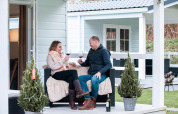 Par nyder vin på verandaen ved Verandah Chalet på Camping Sevink Molen i Holland omgivet af små træer.