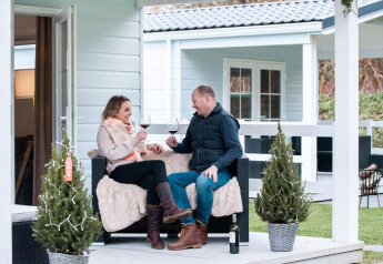 Pareja disfrutando vino en el porche de Verandah Chalet en Camping Sevink Molen, Países Bajos, ambiente acogedor.