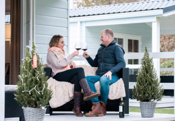 Coppia che brinda con vino rosso sulla veranda del Verandah Chalet al Camping Sevink Molen, Olanda.