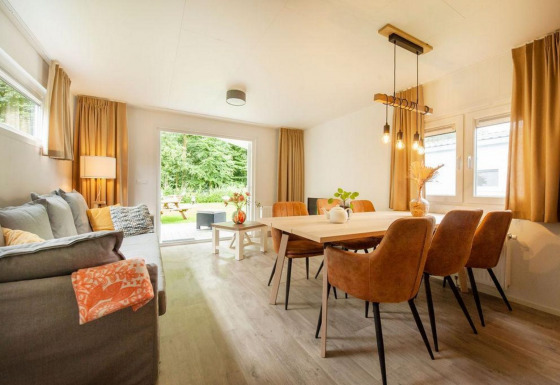 Lichte woon- en eetkamer in een glamping accommodatie met moderne inrichting en uitzicht op de tuin.