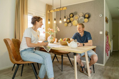 Due persone fanno colazione al tavolo da pranzo nel Verandah Chalet al Camping Sevink Molen, Paesi Bassi.