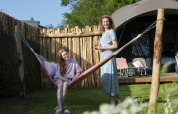 Mother and daughter relaxing by a hammock in front of a lodge at Camping Sevink Molen, Netherlands.