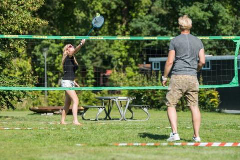 Dos personas juegan bádminton al aire libre en un césped en Jocomo Parc, un parque de vacaciones en Limburgo.