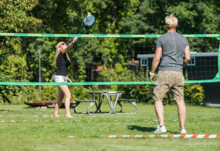 Twee personen spelen badminton buiten op het gras van Jocomo Parc, een vakantiepark in Belgisch Limburg.