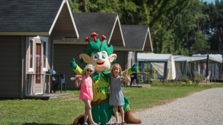 Dos niños posan con una mascota frente a cabañas en Jocomo Parc, un parque de vacaciones en Limburgo, Bélgica.
