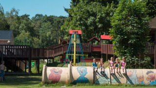 Niños juegan en Jocomo Parc, Bélgica, sobre un tubo pintado en un colorido parque infantil al aire libre.