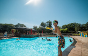 Bambini giocano in piscina sotto il sole al Jocomo Parc, un villaggio vacanze in Limburgo, Belgio.