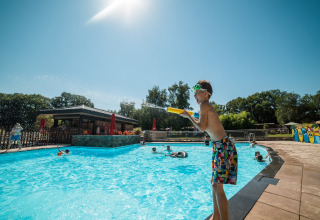 Children playing poolside in bright sunshine at Jocomo Parc, a holiday park in Limburg, Belgium.