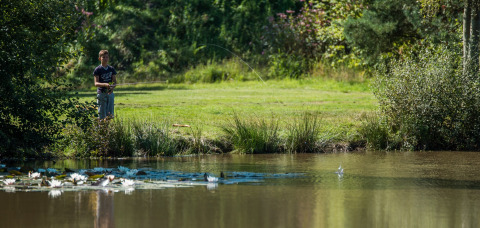 Niño pescando en la orilla de un estanque en Jocomo Parc, un parque de vacaciones en Limburgo, Bélgica.