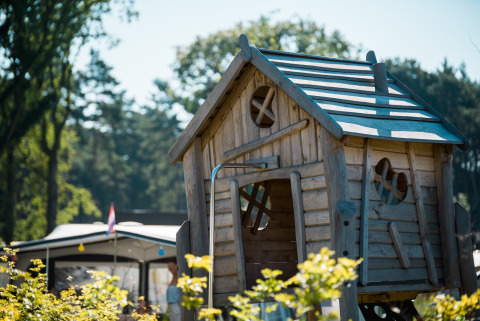 Casita de juegos de madera con ventanas originales en Jocomo Parc, parque de vacaciones en Limburg, Bélgica.