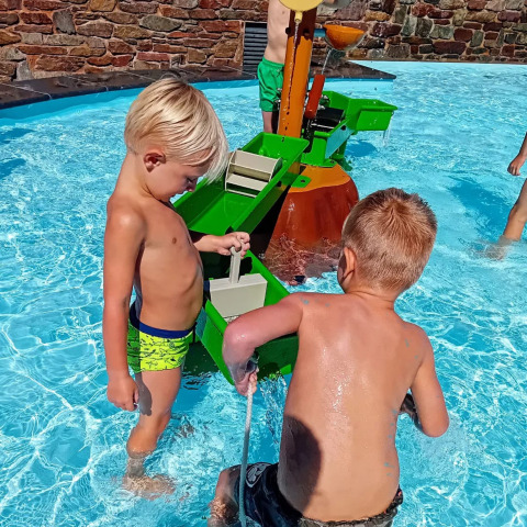 Niños jugando con juegos de agua en una piscina exterior del parque de vacaciones Jocomo Parc, Bélgica.