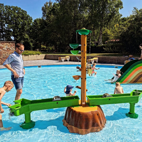 Bambini giocano in una piscina bassa con giochi d’acqua e scivolo a Jocomo Parc, Limburgo belga.