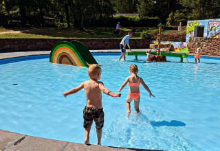 Bambini che giocano e corrono in una piscina bassa a Jocomo Parc, parco vacanze in Limburg, Belgio, in una giornata di sole.