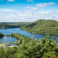 Colinas boscosas y lagos cerca de Lanaken, Bélgica, bajo un cielo azul con nubes blancas y paisaje natural.