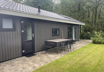 Udendørsbillede af Bos Cottage ved De Thijmse Berg, Holland, med terrasse, bord og stole foran skov.